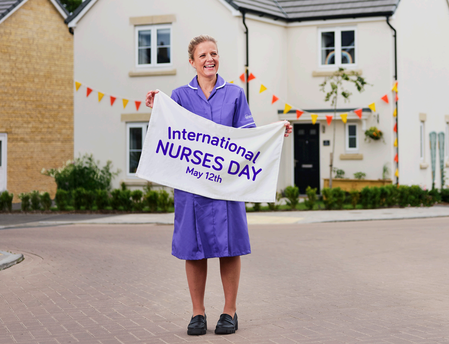 Homeward nurse smiling and holding an International Nurses Day banner